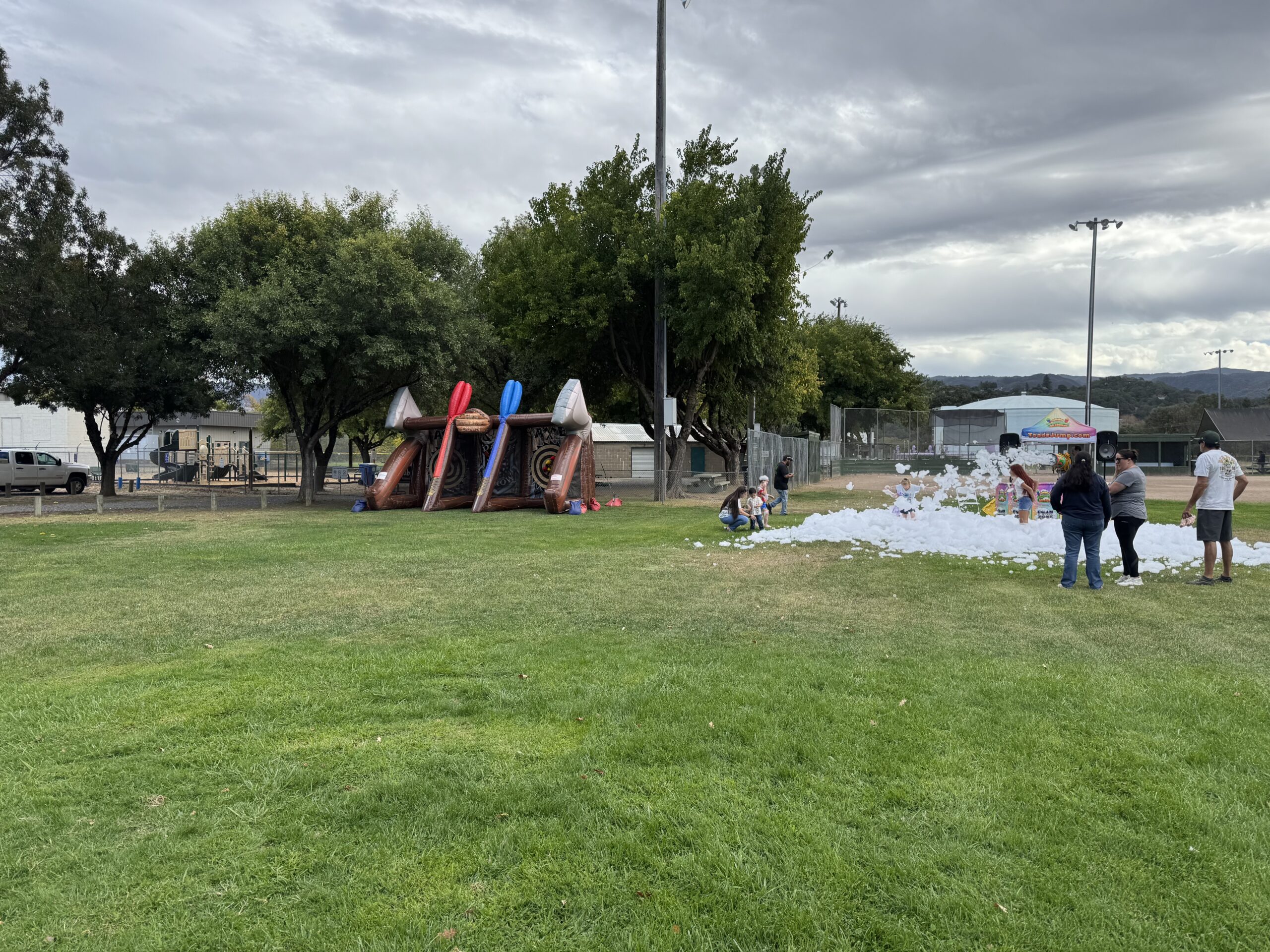 Inflatable games and a foam setup on a grass field at a community event