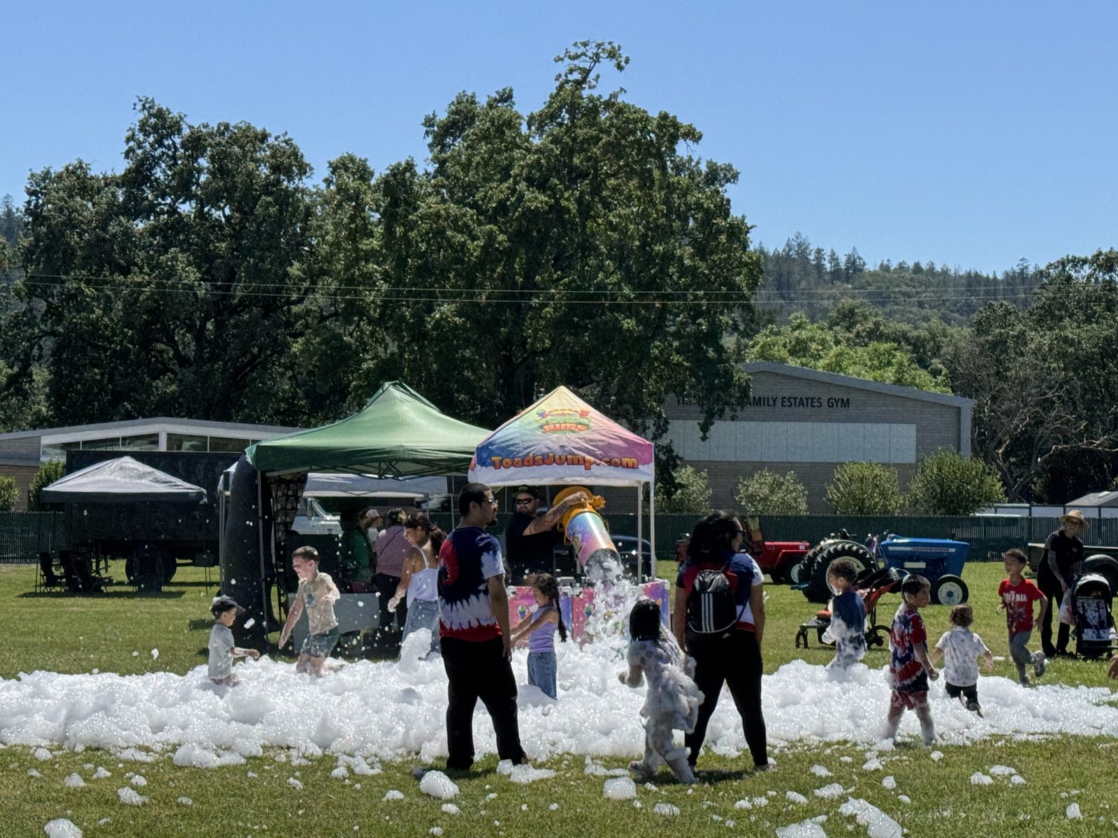Kids playing in foam from a foam cannon under a ToadsJump.com canopy at an event at the Calistoga Fairgrounds