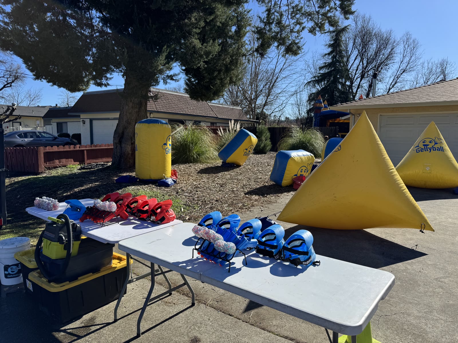 Yellow GellyBall bunkers set up in a yard with masks and blasters on tables
