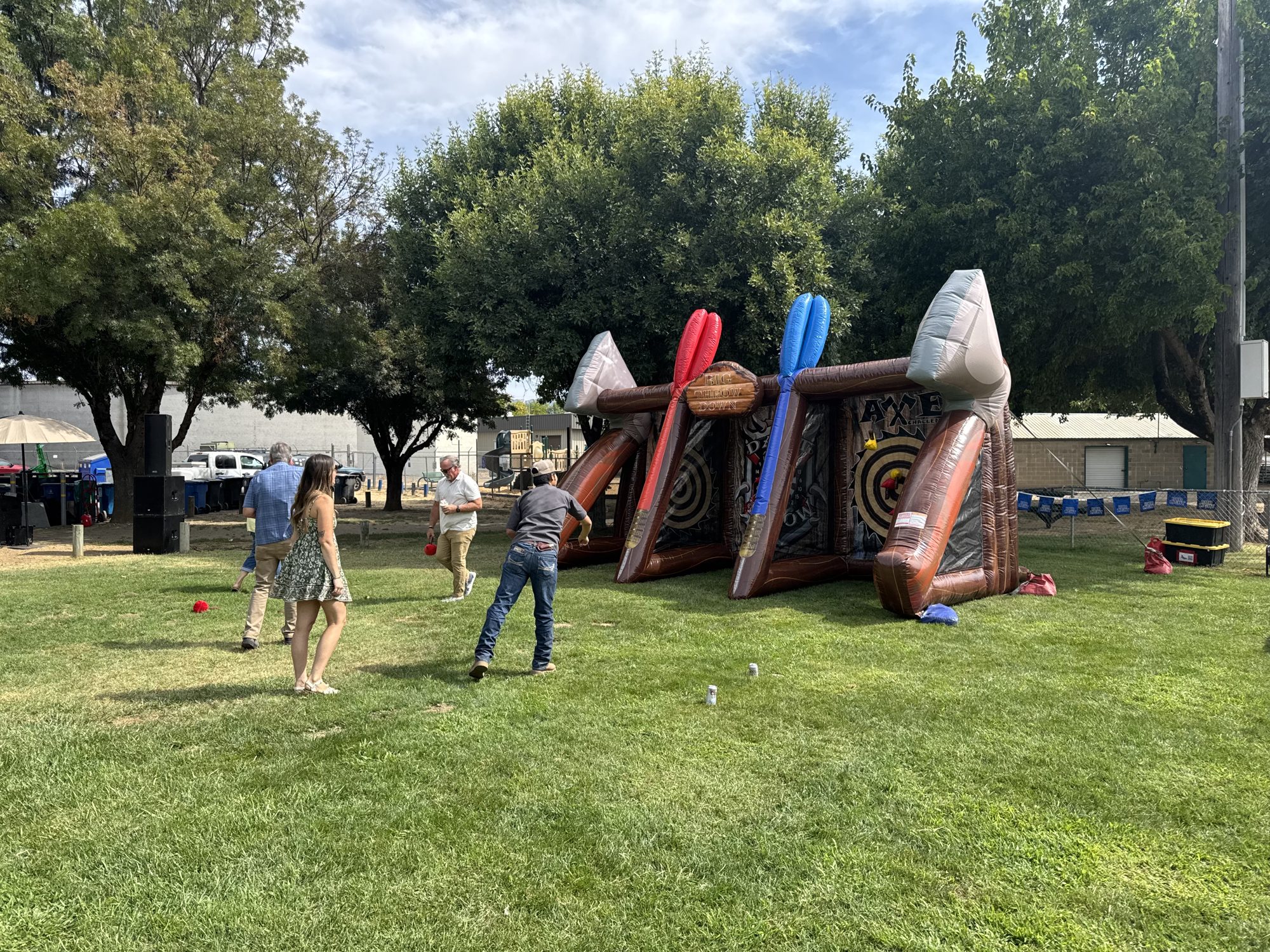 Adults playing an inflatable axe throw game at a park event in Ukiah