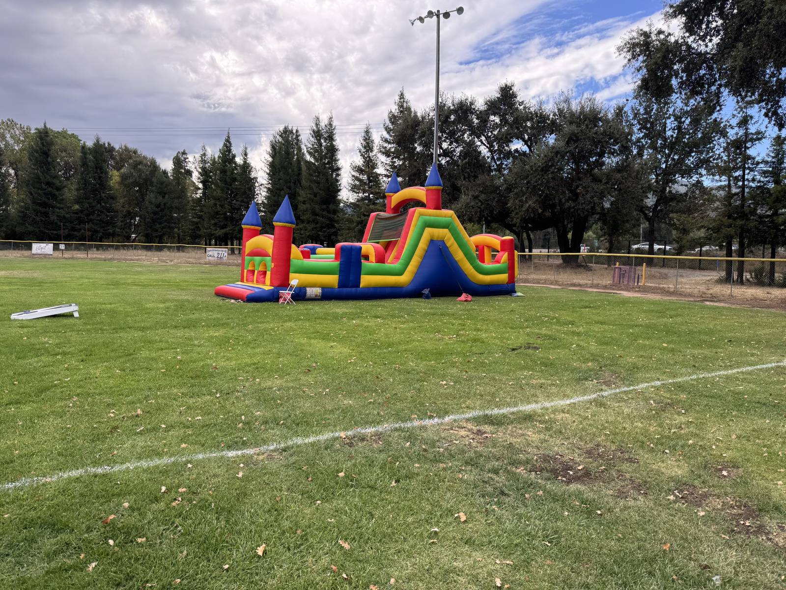 A red, yellow and blue castle obstacle course set up on a park ball field in Ukiah